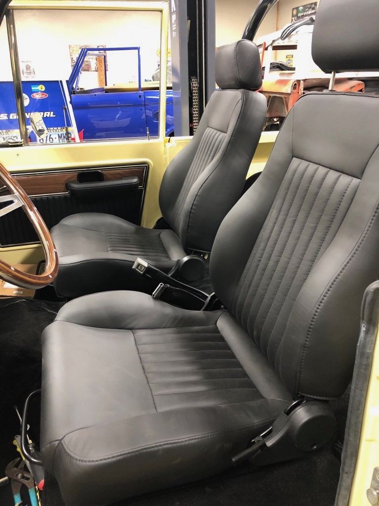 Black custom front bucket seats with the wood-rim steering wheel beyond