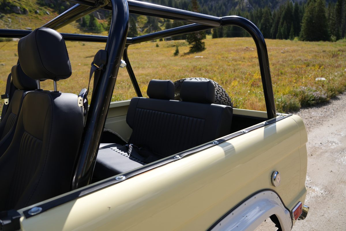 Black front bucket seats with headrests and the full black roll cage, looking back toward the rear bench and spare